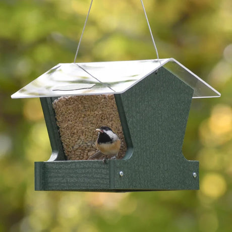 Duncraft Heritage Hopper Feeder, Green, with a chickadee perched on its tray, features clearview panels and metal mesh for drainage, stocked with birdseed.