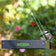 Duncraft Classic Bird Safe Platform Feeder, Black, features a chickadee perched on its edge, suspended by metal wires with a garden backdrop.