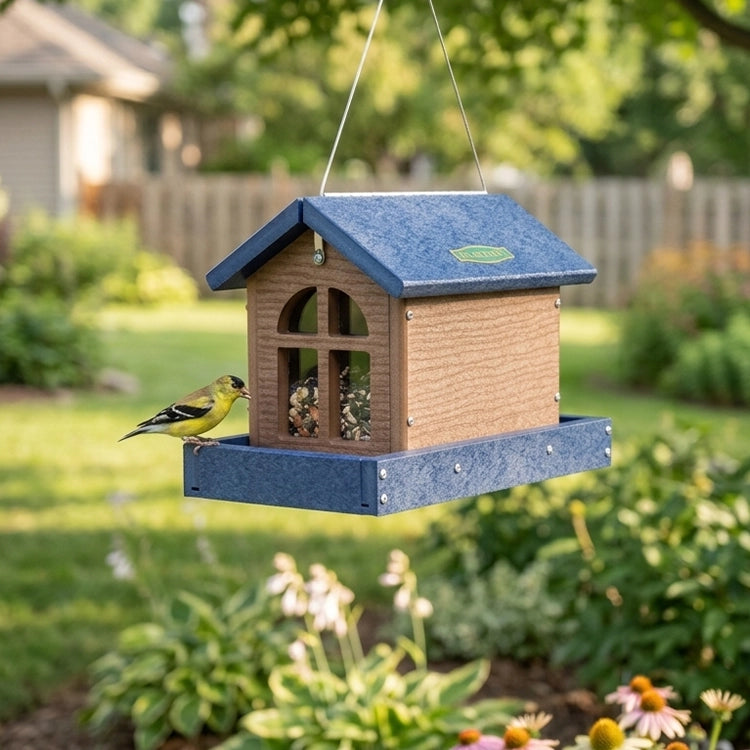 Barn bird feeder with seed and a bird hanging in the backyard. 