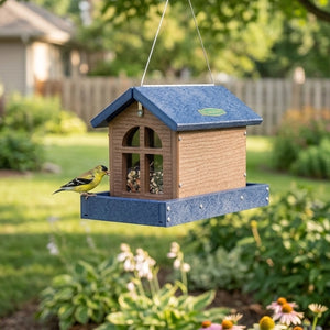 Barn bird feeder with seed and a bird hanging in the backyard. 