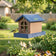 Barn bird feeder with seed and a bird hanging in the backyard. 