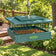 Green Duncraft covered mealworm feeder with wire sides, filled with dried mealworms and hanging in a sunny garden.