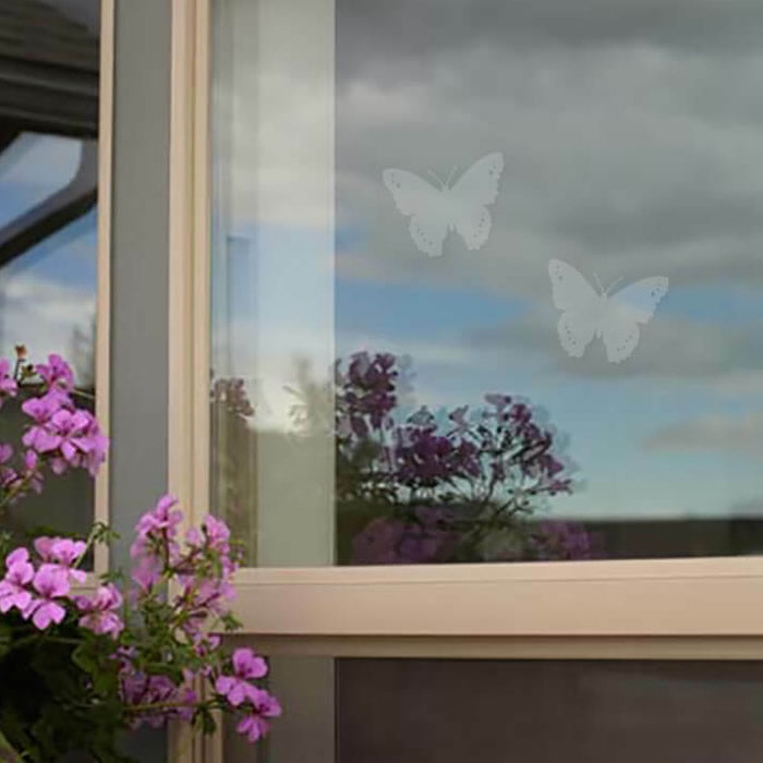 Butterfly WindowAlert Decals, set of 4, displaying UV-reflective butterflies on windows to prevent bird collisions. Translucent design allows clear window views.