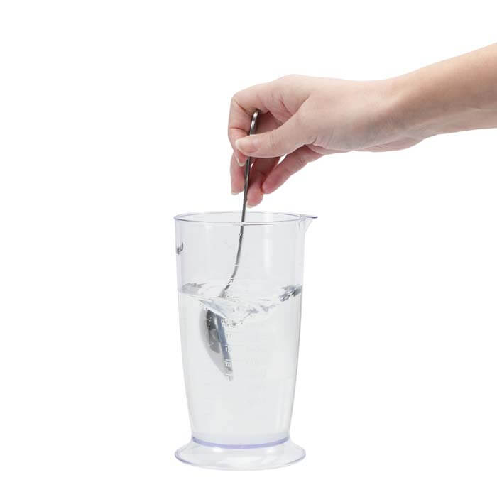 Perky-Pet® Clear Hummingbird Nectar Concentrate, 12 oz., shown with a hand mixing the nectar in a glass of water.