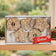Mr. Bird Seed Garland gift box displayed on a wooden shelf beside holiday greenery.