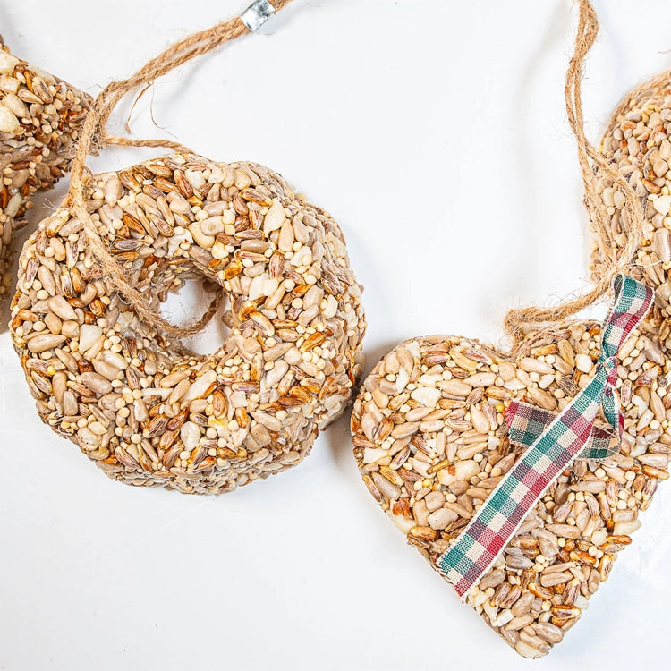 Mr. Bird birdseed garland with star, ring and heart ornaments strung on twine, with a plaid bow on the heart.