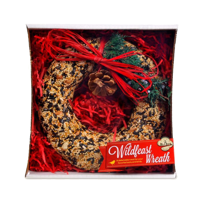 WildFeast Bird Seed Wreath in a box, adorned with a red ribbon and pine cones, offers a nutritious treat for birds, ready to hang.