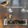 Duncraft Songbird Buffet Window Bird Feeder with a sparrow perched on it, securely attached to a window, showcasing its capacity to attract various bird species.