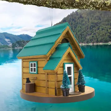 Cedar Point Cottage House, a wooden birdhouse with a green roof, sits on a floating platform. Ideal for small birds, featuring drainage, ventilation, and a hanging wire.