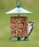 Classic Seed Log Metal Feeder with a woodpecker eating seeds, featuring a bottom perching ring and weather-resistant baffle for year-round bird feeding.