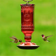 Red Square Antique Bottle Feeder with four feeding ports, attracting hummingbirds, featuring a sparkling square glass design and brushed copper base for easy cleaning.