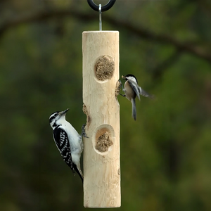 Downy woodpecker and chickadee feeding from a hanging cedar suet log feeder.