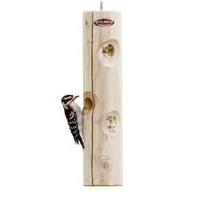 Hanging cedar suet log feeder with a downy woodpecker feeding from recessed suet holes.