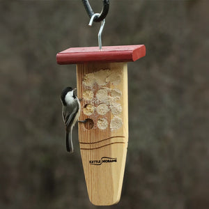 Chickadee enjoying bark butter from a hanging cedar feeder designed for clinging birds.