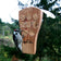 Downy woodpecker feeding from a cedar bark butter feeder with protective clear acrylic roof.