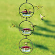 Sphere Hummingbird Feeder, Set of 3, features hummingbirds interacting with red-topped feeders in a durable steel frame, showcasing its capacity to attract birds.