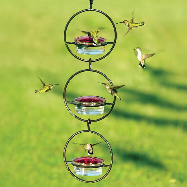 Sphere Hummingbird Feeder, Set of 3, features hummingbirds interacting with red-topped feeders in a durable steel frame, showcasing its capacity to attract birds.