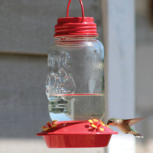 Mason Jar Glass Hummingbird Feeder featuring a clear glass jar, red metal accents, and four feeding ports, designed for easy filling and cleaning.