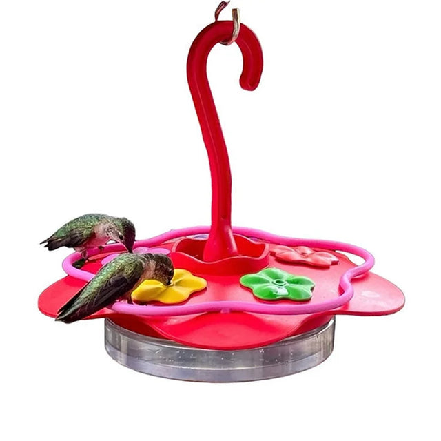 The Glass Sipper Hummingbird Feeder with a circular base and colorful feeding ports, attracting two hummingbirds perched and sipping nectar.
