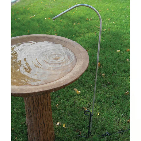 Bird Bath Dripper for Pedestal Bird Bath Stainless Steel, shown with water flowing into a birdbath, set in an outdoor grassy area.