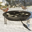 Heated Bird Bath Ground Level with birds, snow-covered, maintaining open water in winter. Features insulated heating coils, black powder-coated steel support ring with tripod legs.