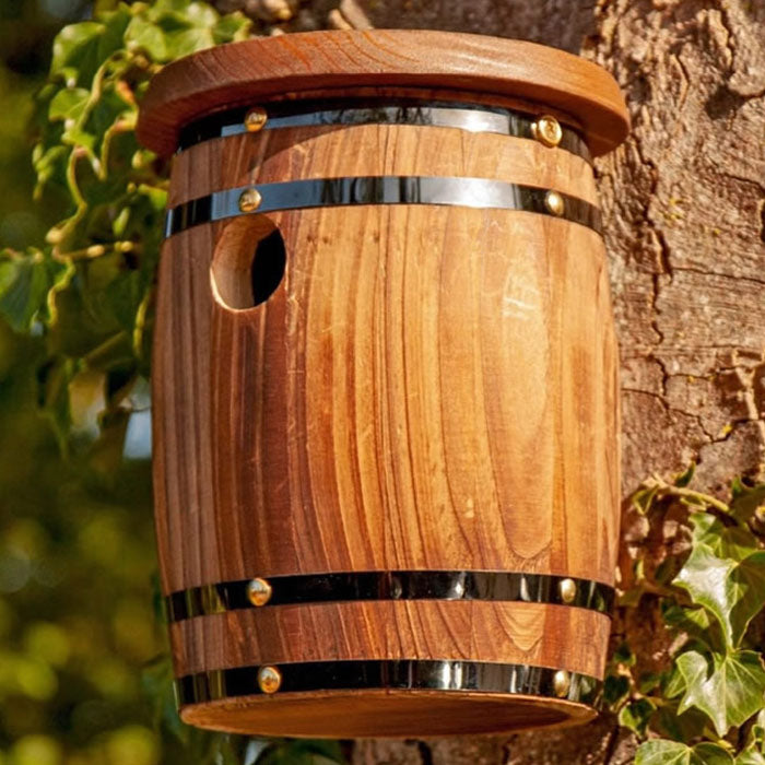 Barrel Bird Nester: A wooden barrel birdhouse with a hole, mounted on a tree, designed for small wild birds.