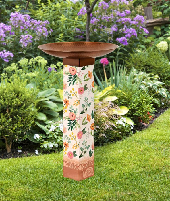 Terra Flora Bird Bath in a garden with a tall PVC post, flower illustrations, and a copper-plated stainless steel basin.