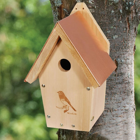 Coppertop Cedar Bluebird House mounted on a tree, featuring a decorative laser-etched bluebird design and a copper roof for heat deflection.