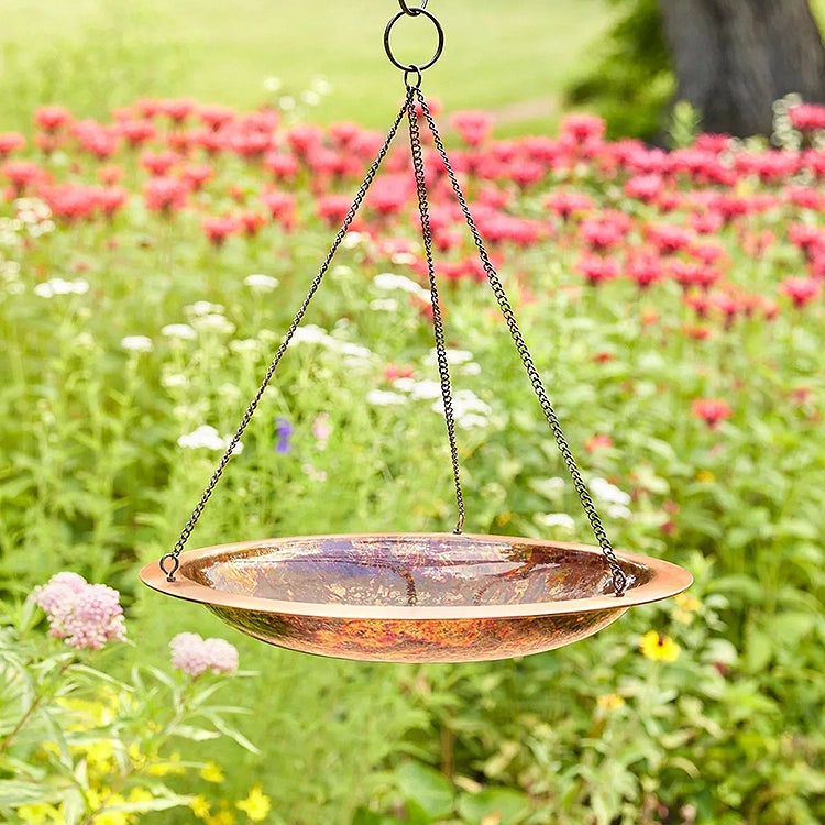 Bronze hanging bird bath with a garden background
