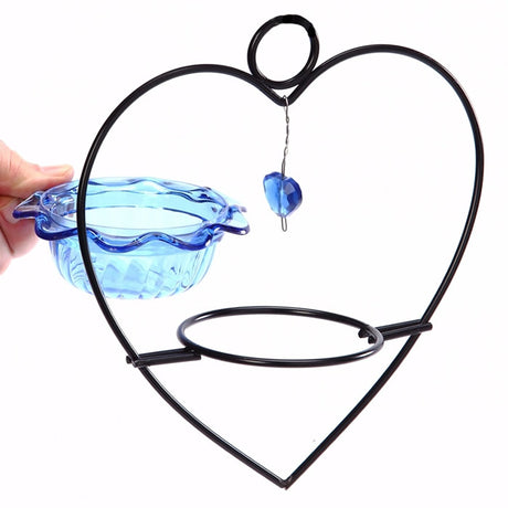 Hand holding Bluebird Heart Feeder, a blue flower-shaped bowl in a heart-shaped metal frame with hanging loop for feeding birds.