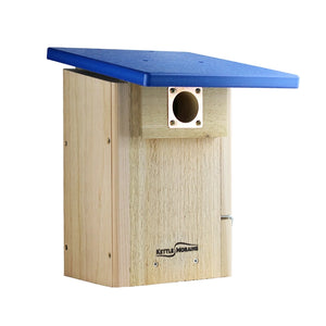 A wooden birdhouse with a light natural wood body and a blue metal roof, featuring a metal entrance hole and the Kettle Moran brand name on the front.