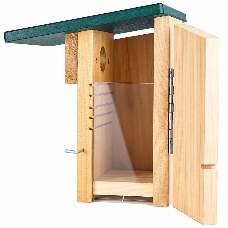 A wooden bird house with an open door, showing a light natural wood body, silver metal hinges, a green roof, and a white interior perch, isolated on a white background.