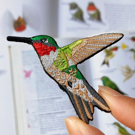 Bird Collective Ruby-Throated Hummingbird Patch: A hand holds a highly detailed embroidered patch of a hummingbird, perfect for sewing onto bags, hats, or jackets.