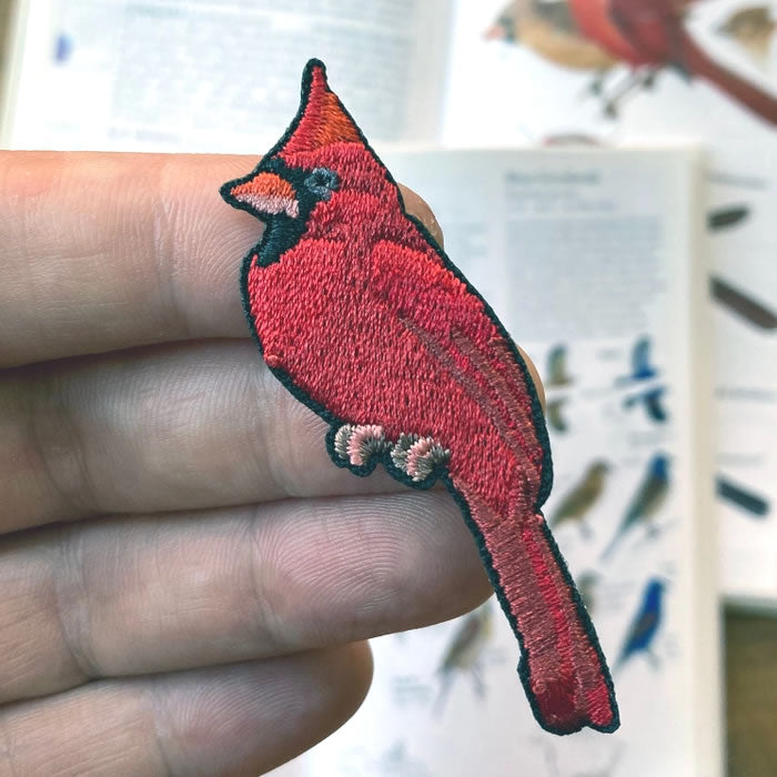 Hand holding the Bird Collective Northern Cardinal Patch, showcasing detailed embroidery of the bird's vibrant red plumage and distinctive markings.