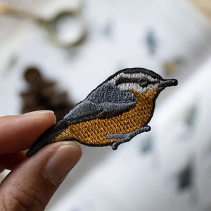 Hand holding Bird Collective Red-Breasted Nuthatch Patch, showcasing intricate embroidery and easy iron-on application for personalizing accessories.