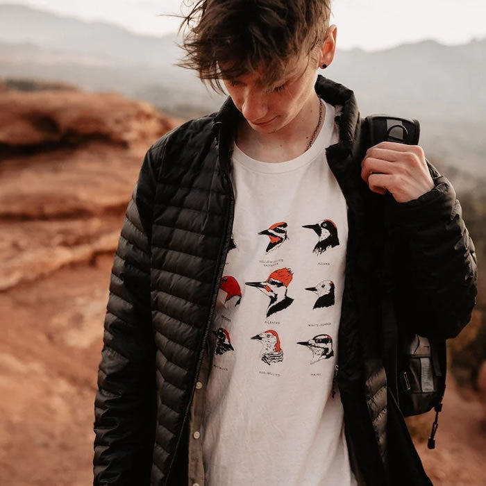 Bird Collective Woodpeckers T-Shirt: A man in a black coat outdoors, showcasing the tee's woodpecker design, perfect for bird enthusiasts and style aficionados.