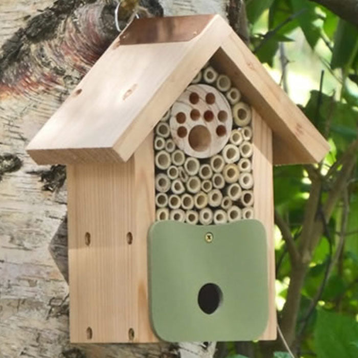 Bee Barn Bee Nester on a tree, featuring multiple entry holes to attract solitary bees and other pollinators, crafted from FSC-certified wood with a recycled plastic frontage.