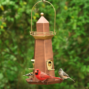 Lighthouse Bird Feeder with a red cardinal perched on it, featuring brass and hand-rubbed copper finishes, spacious base tray, and three perches for multiple birds.