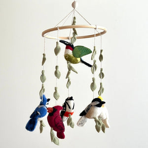 Felt Bird Wings Mobile featuring handcrafted wool-felt birds like a cardinal, hummingbird, and blue jay, adorned with decorative leaves, hanging from a wooden frame.