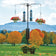 Brome Raccoon Buster® Guardian Pole System with multi-arm design, tubular feeders, and hanging planters in a scenic yard, ensuring raccoon-proof bird feeding.