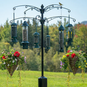 Brome Raccoon Buster Arm Kit Add-On with bird feeders and baskets of flowers hanging on a pole, enhancing outdoor bird feeding setups.