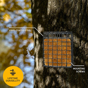 A square black metal bird feeder with a wire grid and tan honeycomb-style insert mounted on a tree trunk outdoors. White callout lines label the product features as 'VINYL COATED STEEL' and 'MOUNTING SCREWS,' with a yellow 'LIFETIME DURABILITY' badge in the lower left.
