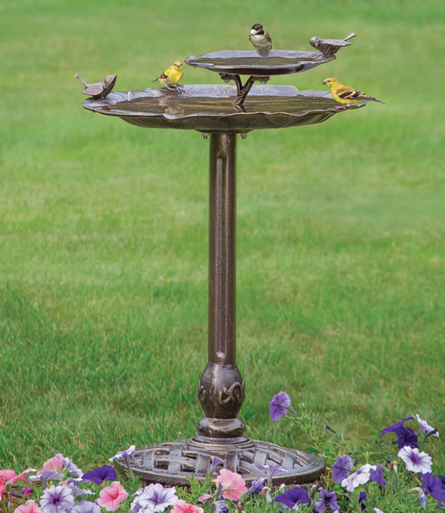 2-Tier Lily Pad Birdbath with birds, featuring textured basins and a stable cast iron base, set in an outdoor grassy area.