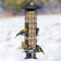 SureFill X4 Bird Feeder with four American goldfinches perched, showcasing its mesh design and squirrel-resistant features in a snowy winter setting.