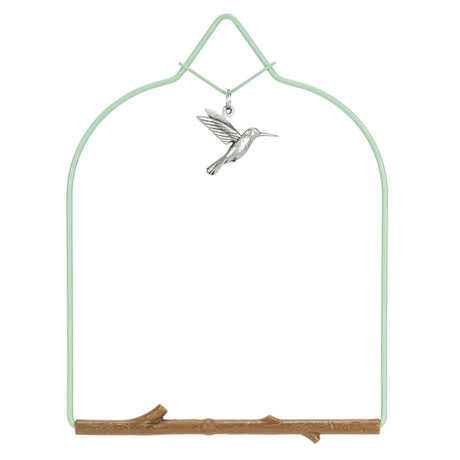 Decorative metal hummingbird on a branch with a green arch background
