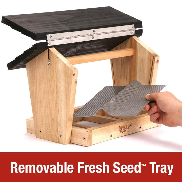 Hand holding a removable seed tray of the Cedar 6 QT Hopper Bird Feeder with Suet, showcasing its drainage and ventilation features.