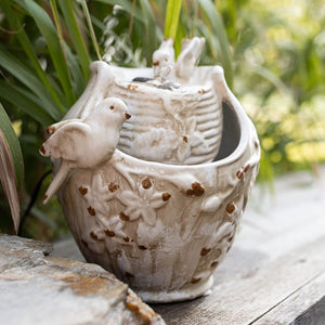 Spring Blooms Fountain: A ceramic bird-shaped fountain with a bird on top, featuring a distressed finish and bubbling water for a tranquil atmosphere.