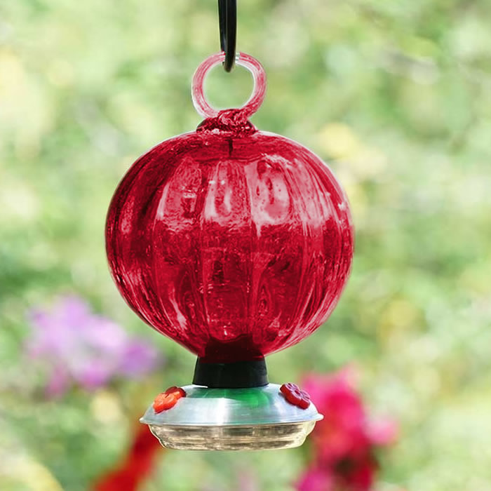 Dew Drop Ruffle Hummingbird Feeder, a hand-blown glass feeder with a silver ring, featuring three red flower feeding ports and a drip-free base.