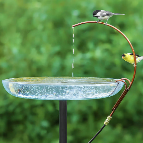 Universal Dripper showcased with chickadee and goldfinch perched on a copper tube, drips water into a glass basin, enhancing your birdbath's appeal.
