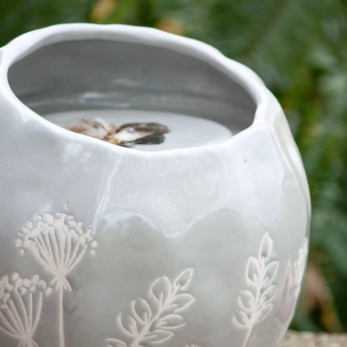 Wildflower Fountain: white ceramic pot filled with water, featuring a gray glossy glaze with delicate botanical shapes, creating a tranquil atmosphere with bubbling water.